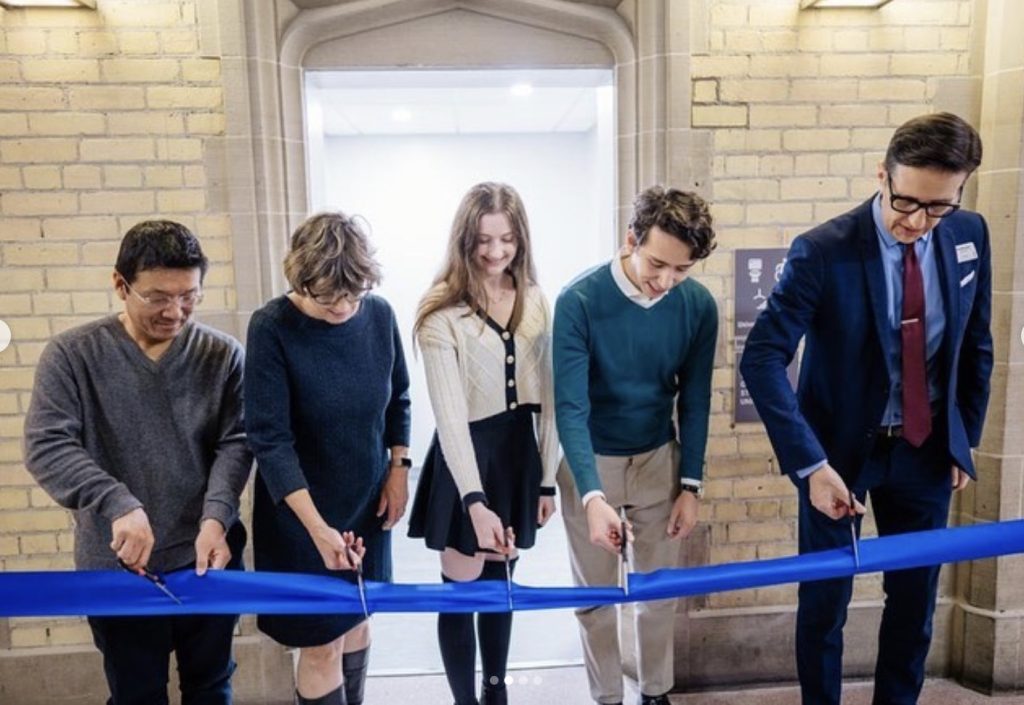 Five people, a mix of U of T students and staff, cutting ribbon to open Hart House's accessible washrooms.